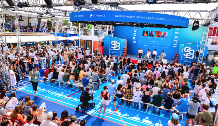 Audience gathered around a basketball court for a live business and sport panel discussion